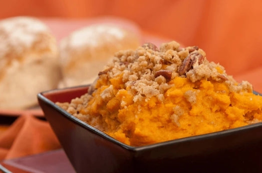 Sweet potato soufflé in a baking dish with golden pecan crumble topping