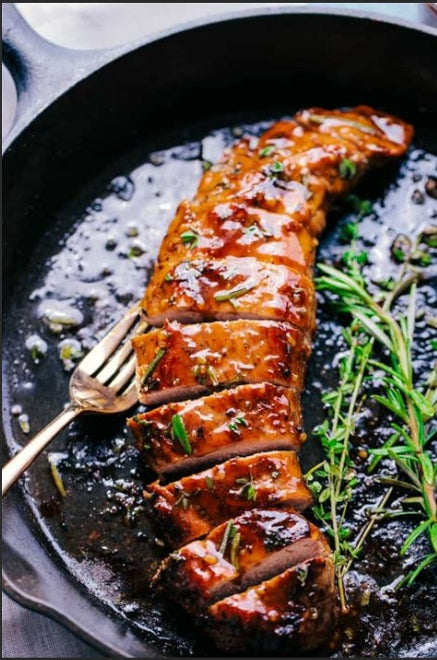 Sliced honey butter garlic pork tenderloin on a cutting board with a honey drizzle